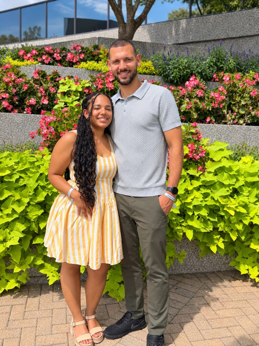 Jordan and Melina smiling together in front of a flower garden
